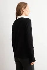 Cardigan de punto fino color negro, con cuello redondo, cierre frontal de botones y mangas largas.