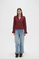 Blusa de viscosa color bordó con diseño bordado geométrico, cuello en V y mangas largas con terminación en volados.