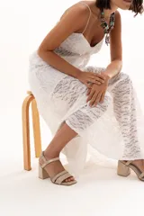 Sandalia de cuero con acabado metalizado dorado, diseño de doble tira delantera y cierre con hebilla ajustable en el tobillo. Cuenta con taco cuadrado y puntera cuadrada.