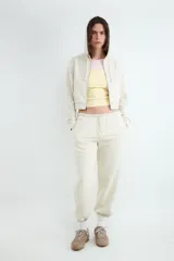 Pantalón jogger color beige, confeccionado en mezcla de algodón y poliéster, con cintura elástica ajustable mediante cordón y puños elásticos en los tobillos.