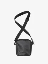 Bolso tipo morral Carhartt en color negro, con correa ajustable y desmontable. Presenta un bolsillo frontal con solapa y cierre de velcro, junto con un compartimento principal con cierre de cremallera. Incluye el logo de la marca en la parte frontal.