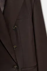 Blazer de corte sastre con cuello solapa, manga larga y hombreras marcadas. Presenta un diseño cruzado con cierre frontal de botones, bolsillos delanteros de vivo y abertura posterior en el bajo.