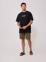 Remera negra de corte oversize, confeccionada en algodón. Presenta un estampado gráfico en el pecho con el logo de la marca y texto complementario.