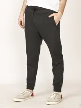 Pantalón de jogging color verde militar, corte slim, con puños elastizados en los tobillos y cordón ajustable en la cintura. Presenta un bolsillo lateral con cierre.