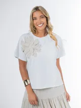 Remera blanca de tejido liviano con aplique de flor de crochet en el frente.