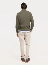 Sweater de punto acanalado en color azul marino, con cuello alto y cierre frontal parcial. Presenta mangas largas con puños acanalados y un pequeño logo bordado en rojo en el pecho.