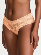 Panty de encaje color salmón, modelo tipo cheeky de tiro bajo con detalles festoneados.
