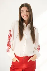 Camisa blanca de mangas largas con bordados florales rojos en las mangas y cuello clásico.