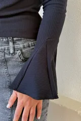 Remera de algodón acanalado color negro, con cuello bote y mangas largas con terminación oxford acampanada.