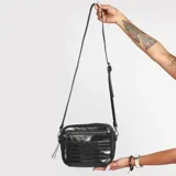 Cartera bandolera negra con textura símil cuero de cocodrilo, correa larga regulable y cierre superior con cremallera.