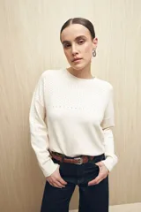 Sweater de punto fino color blanco, con cuello redondo, mangas largas y detalle de calado delicado en la parte superior del pecho, hombros y mangas.