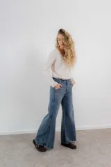 Pantalón de jean con tiro medio y corte de pierna ancha, estilo wide leg. Cuenta con diseño de cinco bolsillos y costuras con pespuntes a contratono.