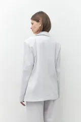 Blazer de lino color blanco, de corte oversize, con solapas de muesca y cierre con dos botones.