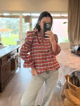 Camisa de manga larga con estampado de cuadros en tonos rojos, blancos y azules. Presenta un diseño con mangas abullonadas divididas por secciones elásticas y cierre frontal con botones.