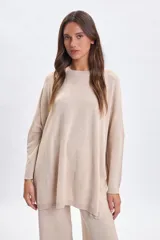 Buzo de punto oversize color beige, con cuello redondo, mangas largas y corte holgado.