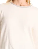 Buzo blanco de tejido liviano soft, marca Pinch. Cuello a la base realzado con una banda de micro-strass plateado. Mangas largas de corte recto con terminación de puño fino.