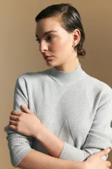 Polera de cuello alto en color blanco, confeccionada en tejido acanalado con un diseño geométrico de relieve que crea un efecto visual estilizado. Presenta un corte al cuerpo y mangas largas, ideal para usar como prenda base o principal.