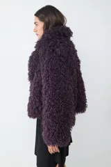 Campera corta de pelo sintético con textura rizada y voluminosa, de corte holgado y diseño envolvente.