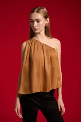 Blusa de poliéster color negro, con diseño asimétrico de un solo hombro, plisado ligero y corte holgado.