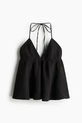 Top halter de algodon negro en muselina con escote en V y tiras que se anudan en el cuello. Presenta un diseño con costura fruncida debajo del busto y silueta acampanada.