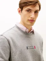 Buzo de cuello redondo Tommy Hilfiger, color gris melange, con diseño clásico y detalles acanalados en cuello, puños y bajo. Cuenta con un pequeño logo gráfico estampado y bordado en el centro del pecho.