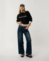 Buzo Rip Curl de punto color negro con diseño de bloques de color, presenta paneles en color crudo en los puños, cuello y el borde inferior. Incluye la inscripción "Rip Curl" bordada en el pecho con tipografía estilo gótico.