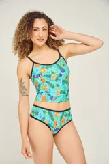 Tankini estampado con hojas, flores y tucanes, con breteles finos regulables y contorno negro.