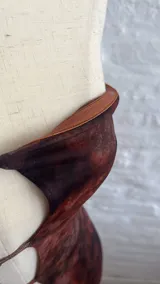 Vestido corto marrón con estampado animal print, corte ajustado, escote strapless con aberturas en el frente y breteles finos.