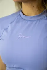 Remera deportiva de lycra color lila, de corte crop top, cuello redondo y mangas cortas.