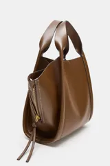 Bolso bandolera de formato city color marrón, con diseño estructurado, pespuntes decorativos, doble asa de mano y cremalleras laterales con tiradores colgantes.