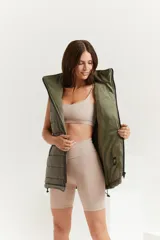 Chaleco verde militar con cierre frontal, bolsillos laterales y capucha forrada.