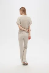 Pantalón acampanado de poliéster y lurex, color beige, de tiro alto y corte holgado.