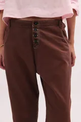 Pantalón de jean de tiro bajo y calce relajado, con cierre frontal de múltiples botones visibles y largo al tobillo.