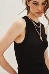 Top sin mangas con cuello halter, confeccionado en tejido de punto con acabado metalizado. Presenta un ajuste al cuerpo y diseño minimalista.