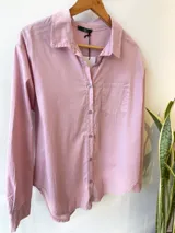 Camisa celeste de corte holgado, con cuello clásico, cierre frontal con botones, bolsillo en el pecho y mangas largas con puños abotonados.