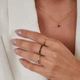 Collar de oro 18k con cadena fina de eslabones y dije ovalado central que presenta un zafiro azul rodeado por pequeños brillantes.