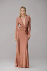 Vestido largo de color salmón, con escote profundo en V, mangas largas y detalle de drapeado lateral en la cintura que cae con fluidez.
