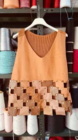 Top color ocre con frente de cuero y espalda tejida de punto. Presenta apliques de piezas de cuero unidas con tachas.