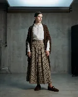 Ruana triangular tejida en telar, de color marrón oscuro, con terminación de flecos en los bordes.