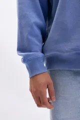 Buzo deportivo de cuello redondo, color azul medio con efecto lavado, de corte holgado y manga larga.
