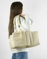 Bolso tipo tote color beige con diseño acolchado y doble asa de hombro.