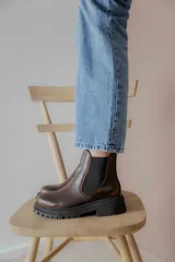 Botas tipo Chelsea de cuero con acabado vintage, diseño de caña media con paneles elásticos laterales y suela track robusta.
