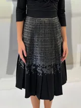 Falda midi de lana estampada a mano con engomado brillante tono sobre tono y tablas irregulares hechas a mano. Tiene bolsillos laterales.