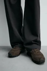 Zapatilla deportiva de hombre confeccionada en piel con acabado de serraje. Presenta un diseño de paneles combinados, cierre con cordones y suela dentada de goma.