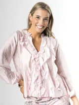 Camisa de organdí rosa pastel con finas rayas verticales metalizadas, escote en V con volados frontales y mangas largas abullonadas con puños elásticos.