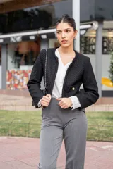 Pantalón de vestir gris de corte recto y largo tobillero, con detalle de botones dorados en los laterales y bolsillos.