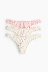 Pack de tres bombachas tipo colaless de tiro bajo con cintura en V y bordes con ribete sobrehilado. El set incluye una prenda lisa en color rosado, una prenda lisa en color crema y una prenda estampada con pequeños corazones rojos sobre base crema.
