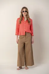 Pantalón ancho color marrón, de tiro alto, con detalle de costuras bordadas en color naranja en ruedo y cintura.