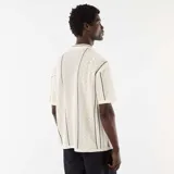 Camisa de manga corta confeccionada en tejido de punto fantasía color beige, con cuello camisero, cierre frontal de botones y detalles de líneas oscuras en zigzag.