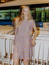 Vestido corto con cuello tipo camisa, manga corta con volados y corte con frunce en la cintura. Presenta un estampado de ondas en tonos rosado, lila y verde oliva.